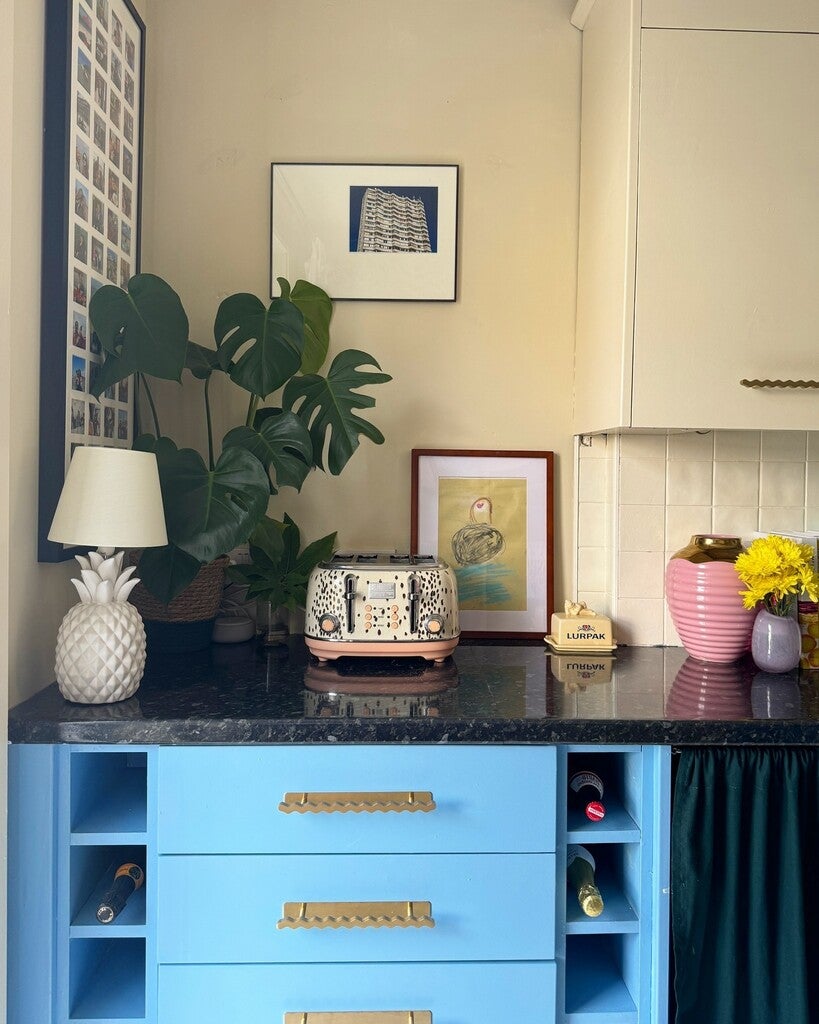 Blue kitchen island with granite countertop, decorative items, and framed pictures on a wall.