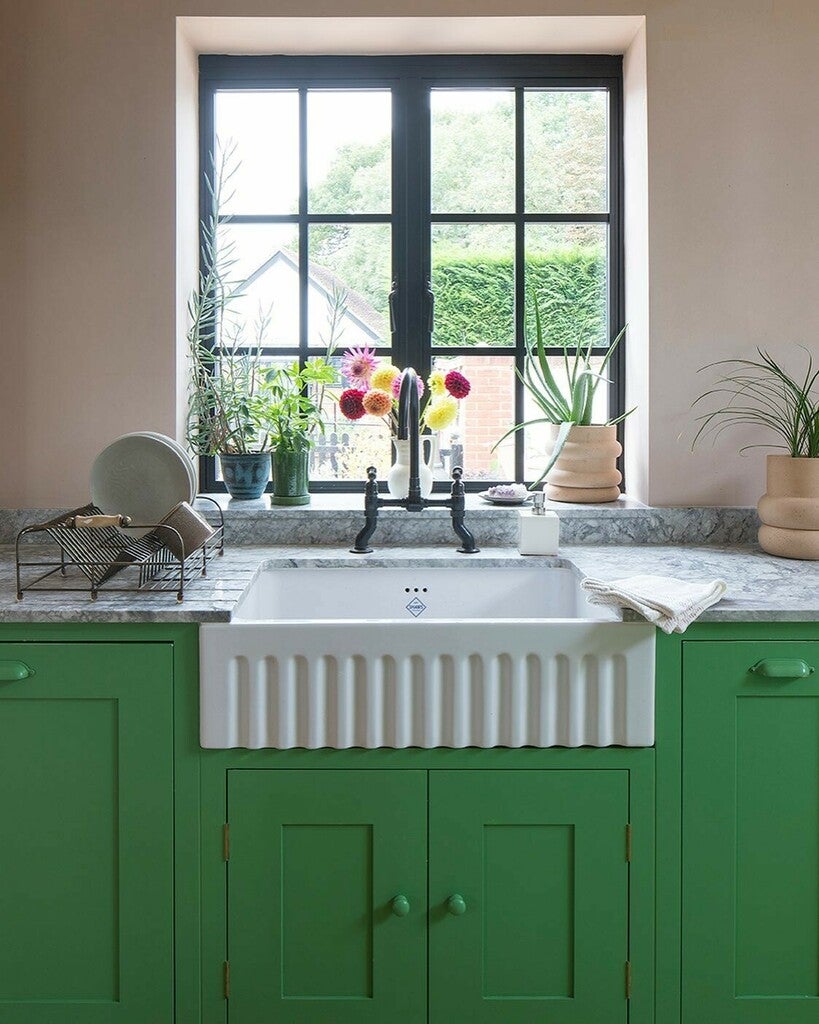 Green kitchen with a white sink and window view