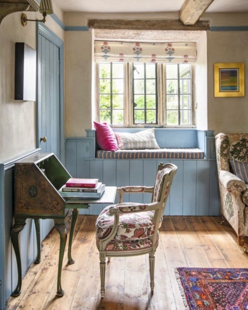 Cozy living room with a window seat, floral chair, and desk.