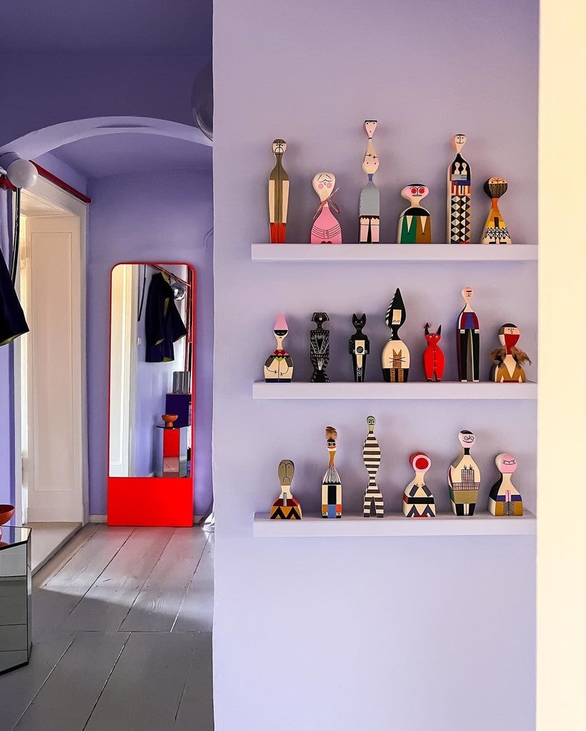 Shelves with decorative bottles against a light purple wall.