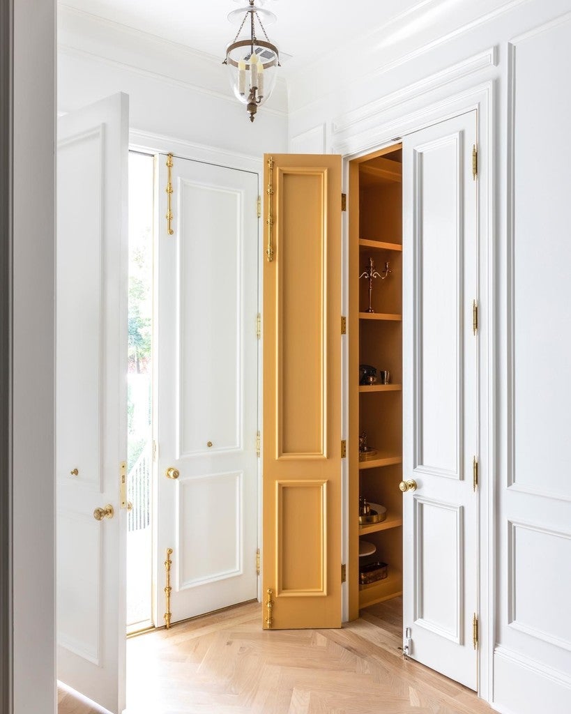 Open pantry with wooden doors in a bright room