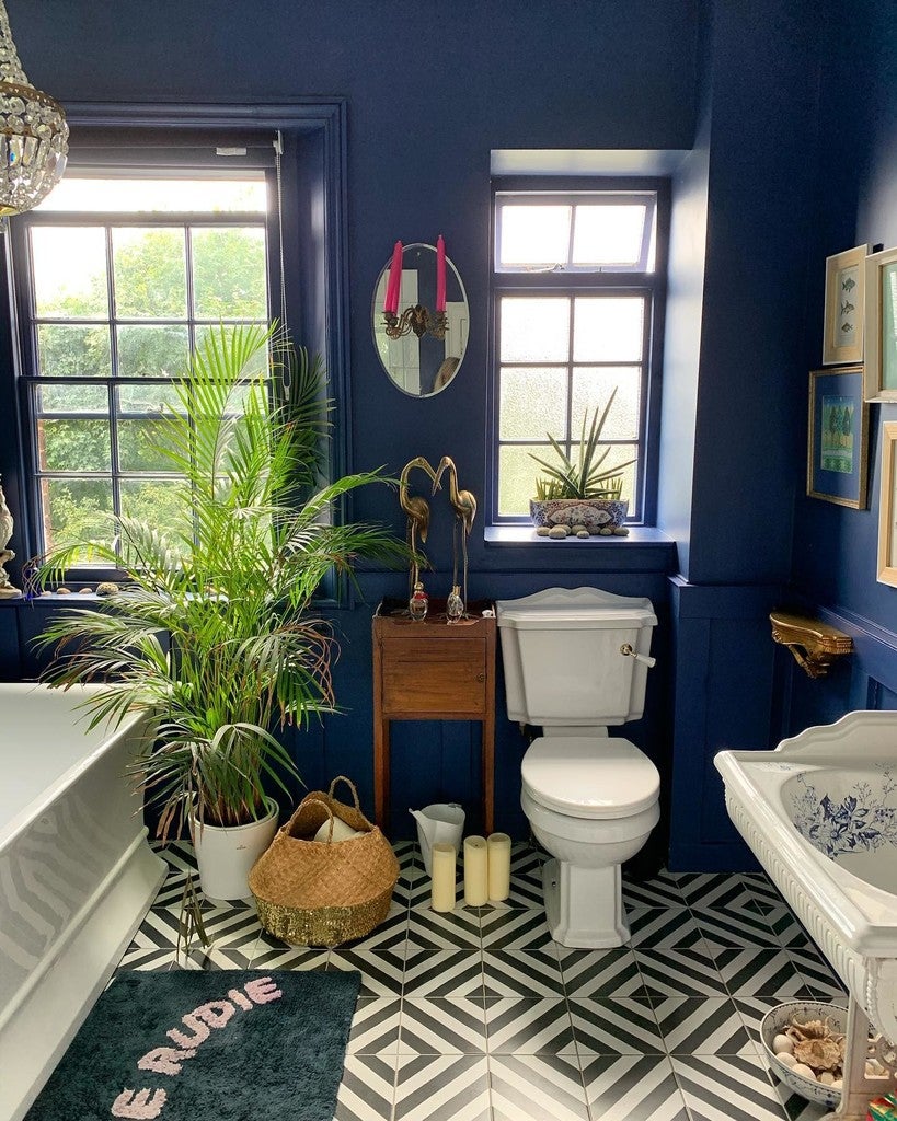Bathroom with blue walls, white fixtures, and decorative elements.
