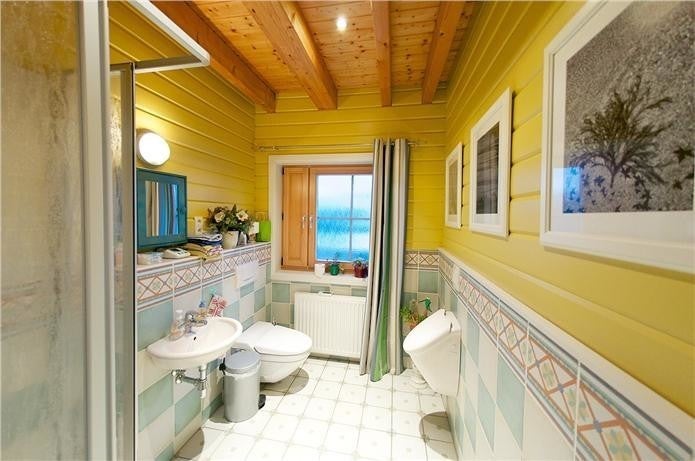 Bathroom with yellow walls, tiled floor, and various fixtures.