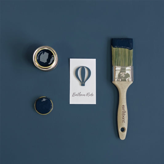 Paint can, brush, and card with a hot air balloon design on a blue background