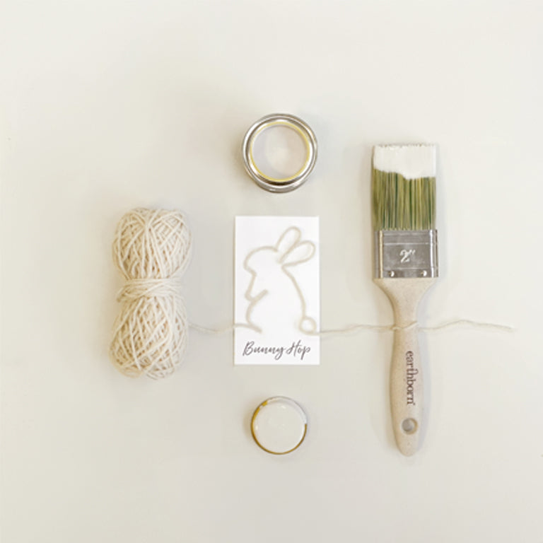 Craft supplies including yarn, rings, and a paintbrush on a white background