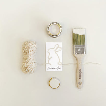 Craft supplies including yarn, rings, and a paintbrush on a white background