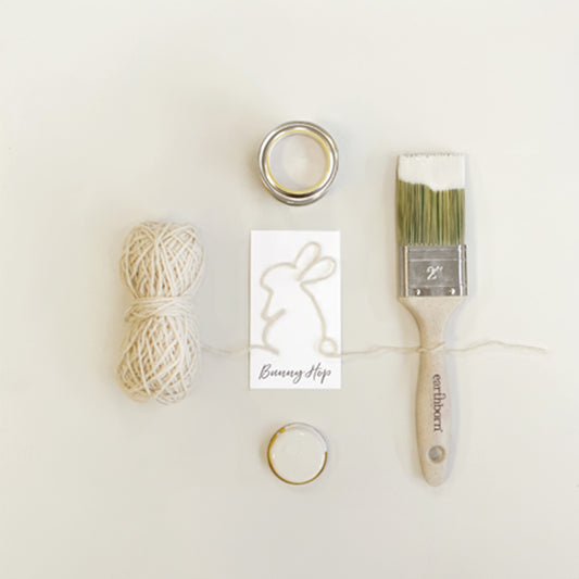 Craft supplies including yarn, rings, and a paintbrush on a white background