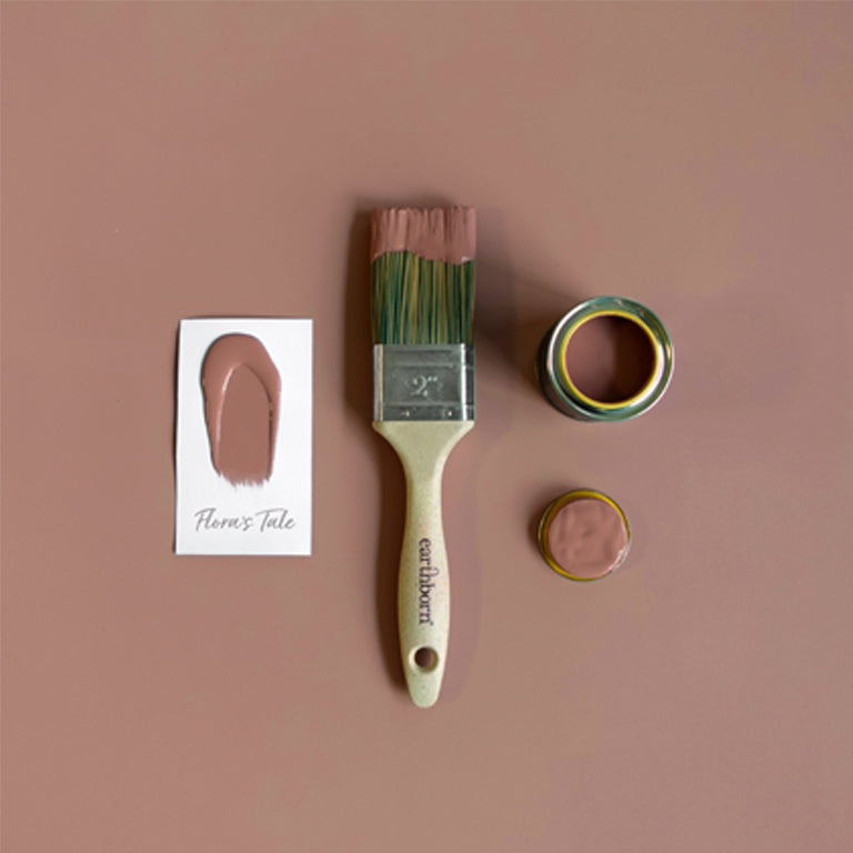 Paintbrush with pink paint and color swatch on a brown background