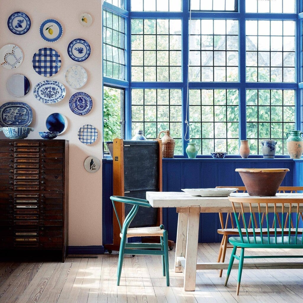 Dining room with blue and white decorative plates on the wall, a table, and chairs.