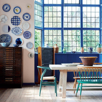 Dining room with blue and white decorative plates on the wall, a table, and chairs.