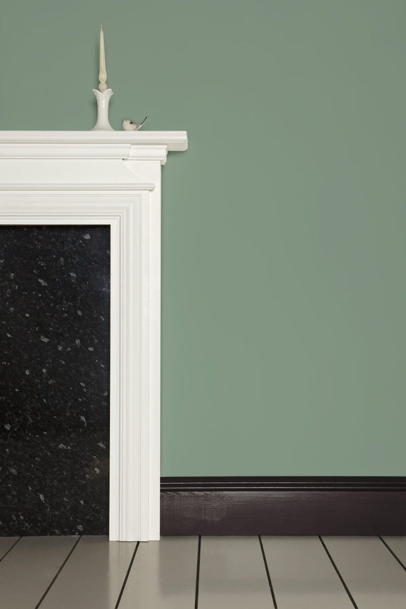 White fireplace with black marble insert against a green wall