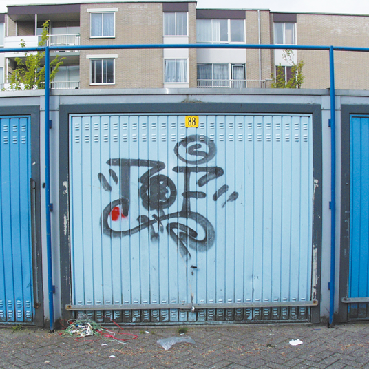 Graffiti on a blue metal gate with a building in the background
