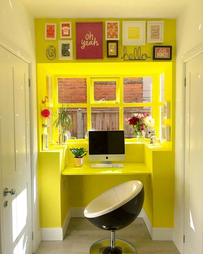 Yellow office nook with a computer setup and decorative elements.