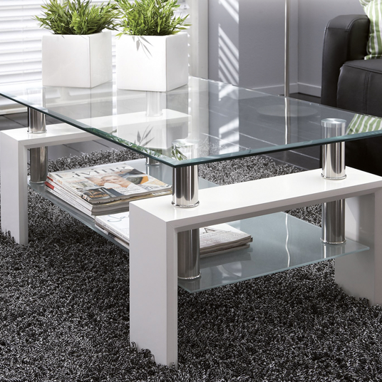 Modern glass coffee table with a white base in a living room setting.