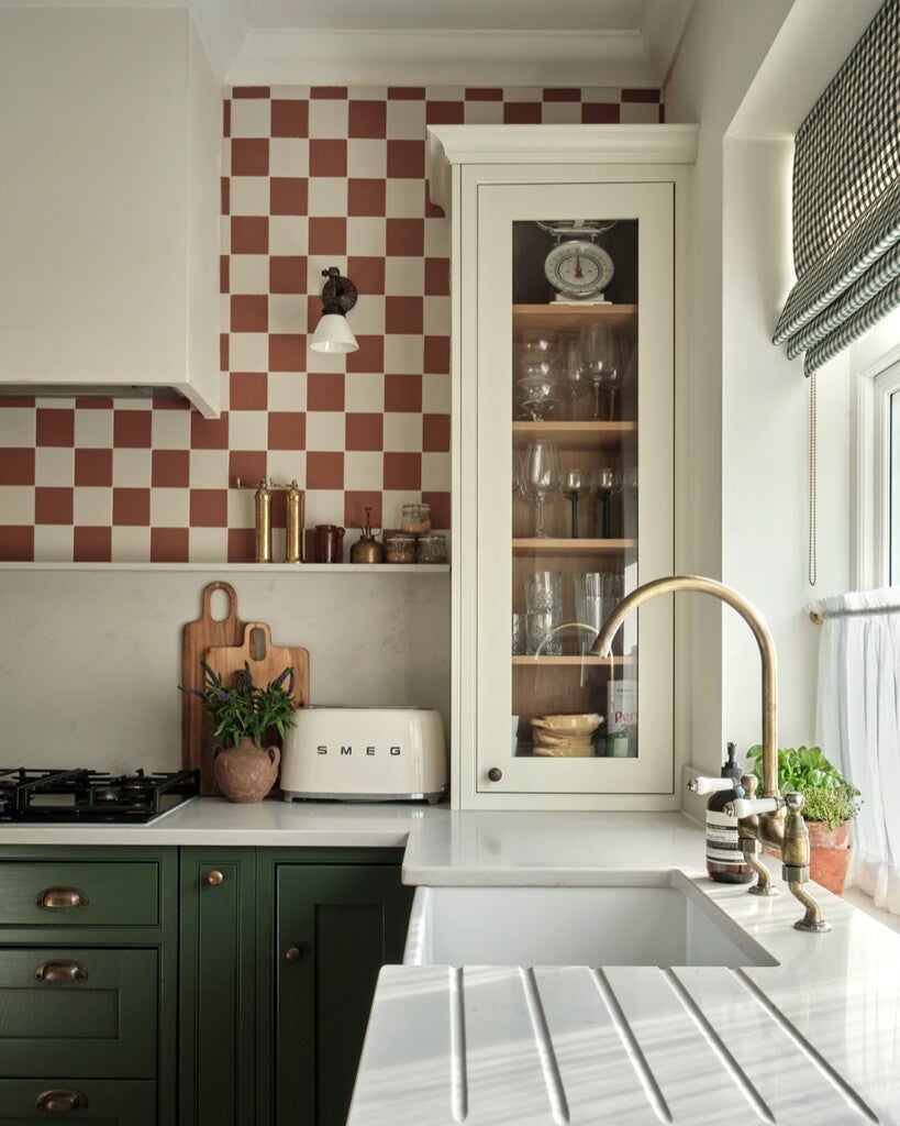 Modern kitchen with green cabinets, white countertop, and checkered backsplash.