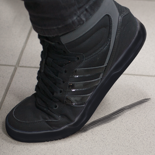 Black high-top sneaker worn on a light gray tiled floor