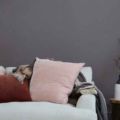 Light gray sofa with pink pillow and blankets against a dark gray wall