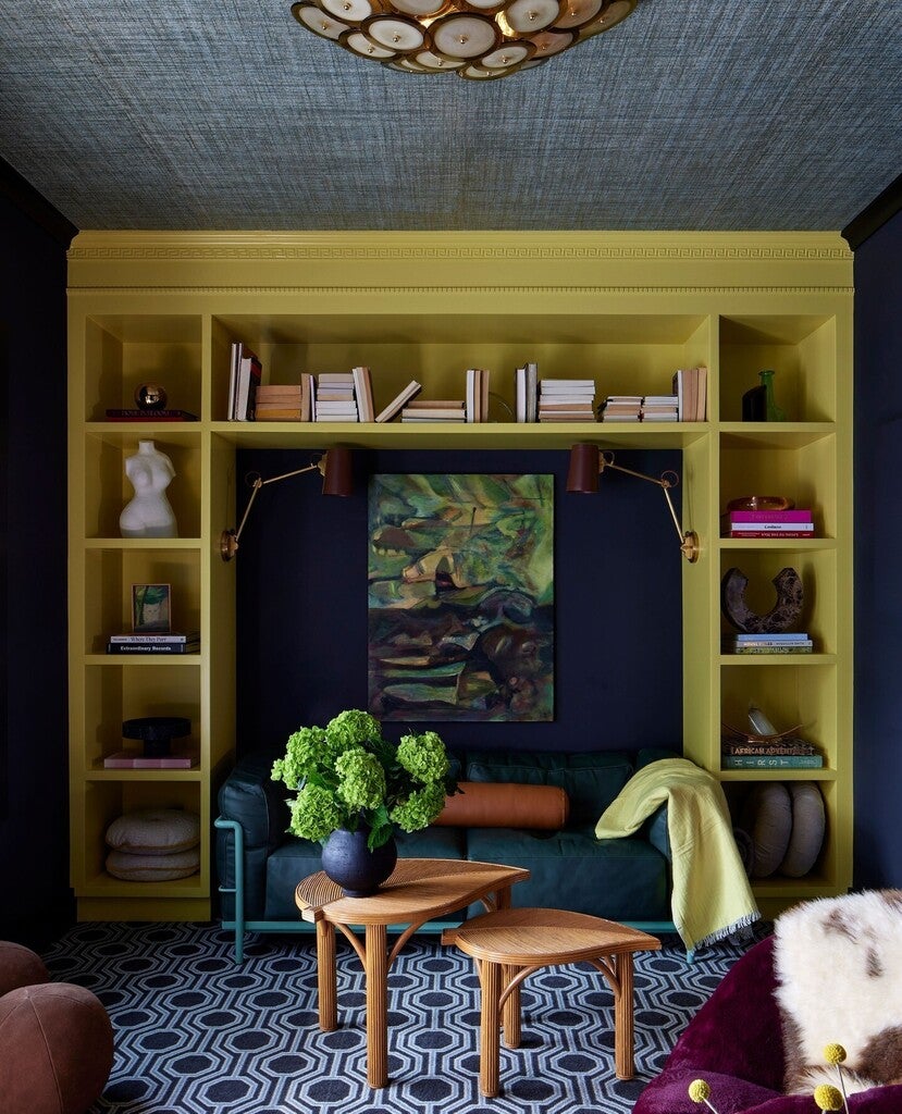 Living room with yellow bookshelf, green sofa, and decorative elements.