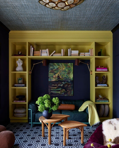 Living room with yellow bookshelf, green sofa, and decorative elements.