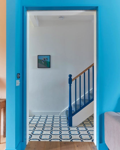 Blue door leading to a room with a patterned floor and staircase.