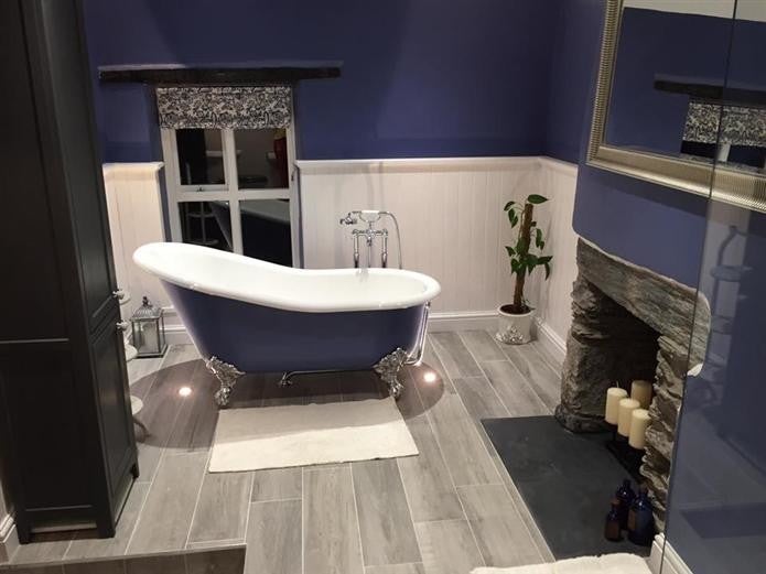 Bathroom with a blue freestanding bathtub, fireplace, and decorative elements.