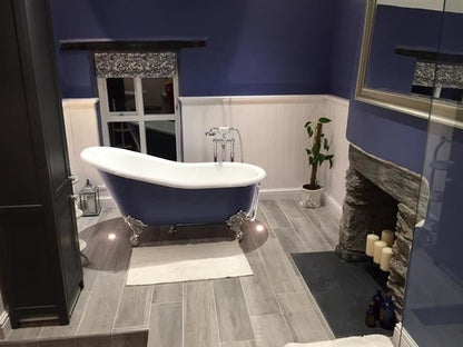 Bathroom with a blue freestanding bathtub, fireplace, and decorative elements.