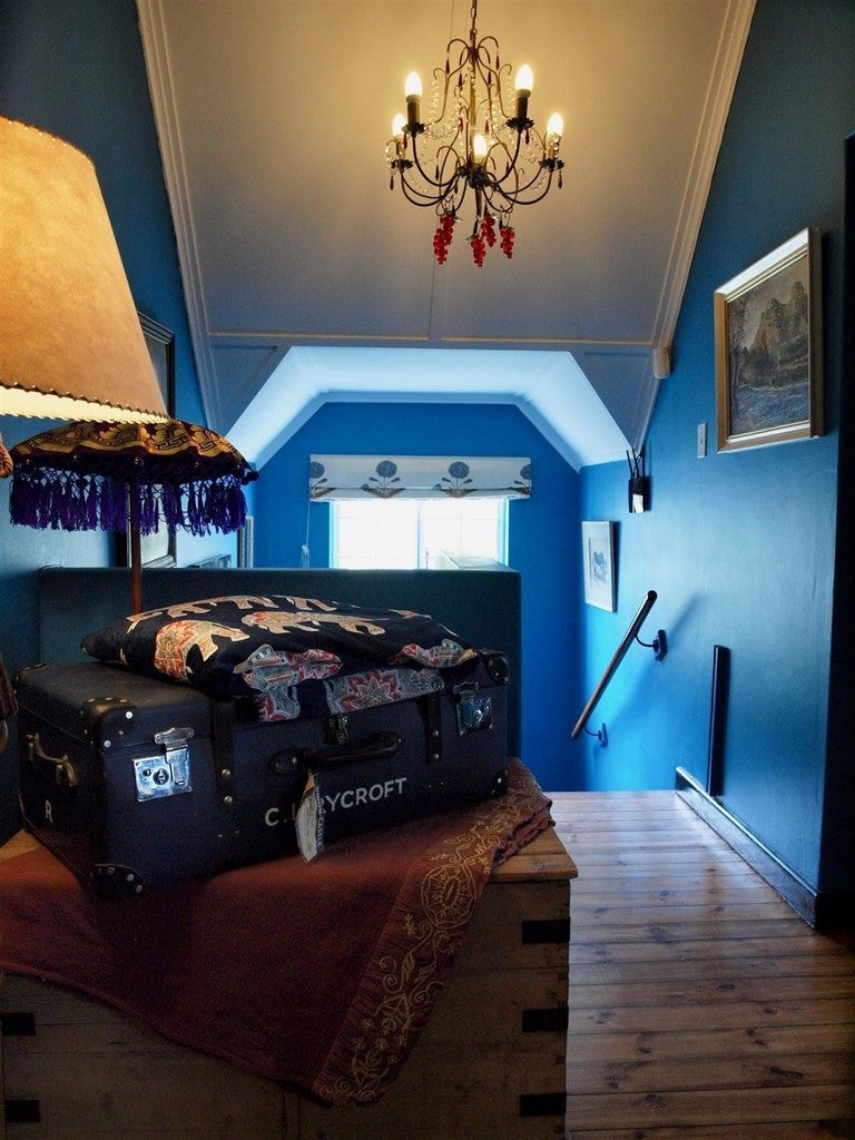 Blue room with a chandelier, suitcase, and lamp.
