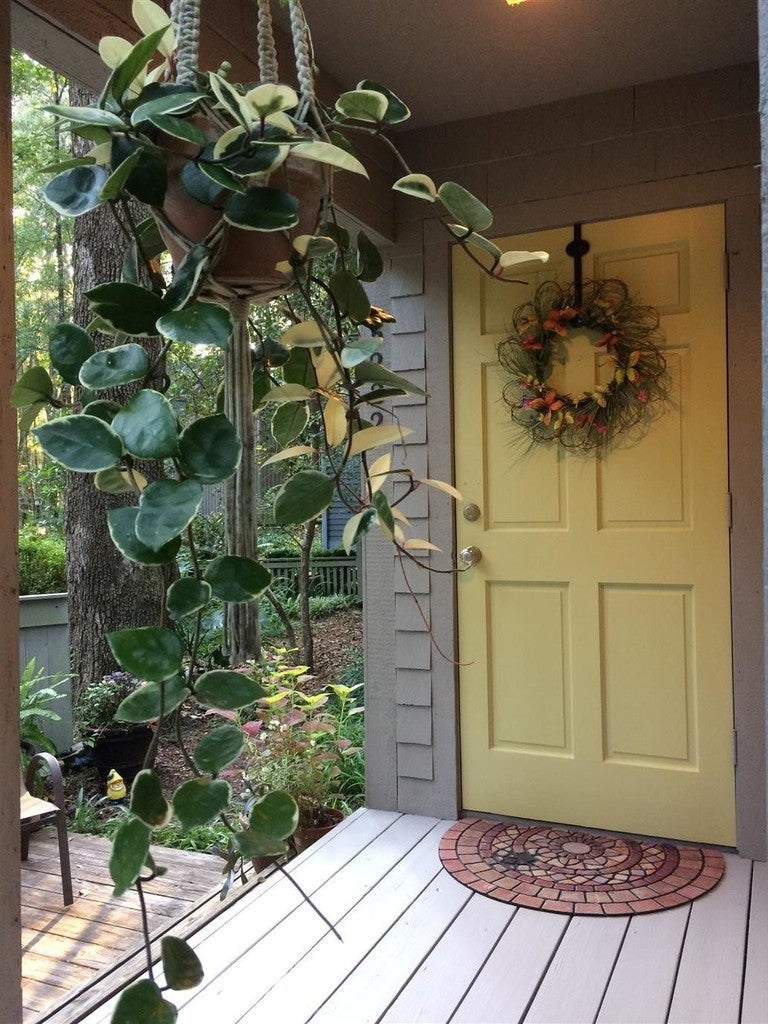 Front porch with a yellow door, wreath, and hanging plant
