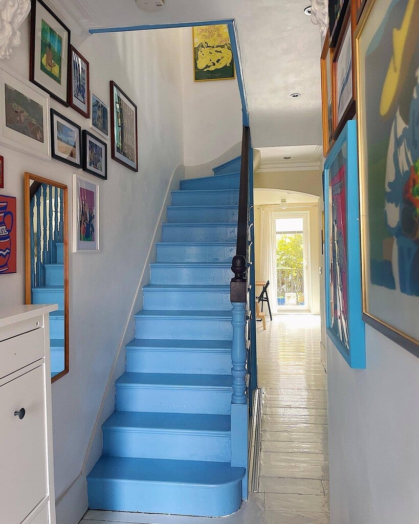 Blue staircase with framed artwork on white walls