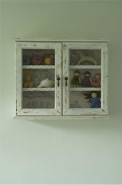 Vintage-style white cabinet with glass doors displaying decorative items against a light green wall.