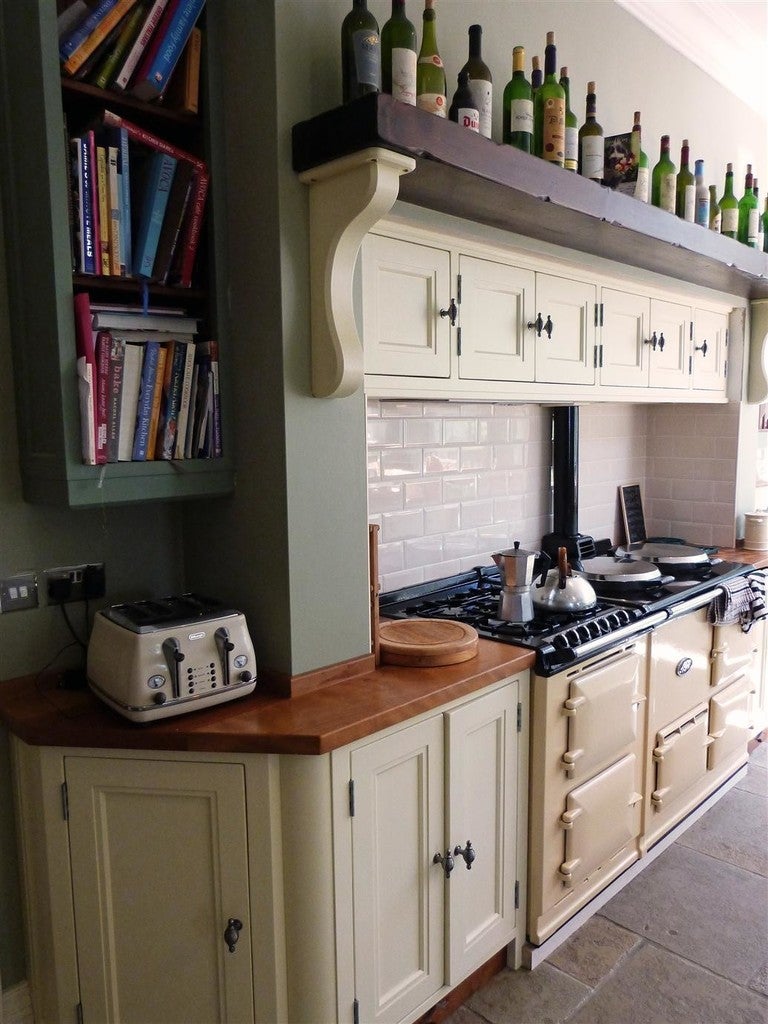 Kitchen with Aga range cooker, wooden countertop, and bookshelf.