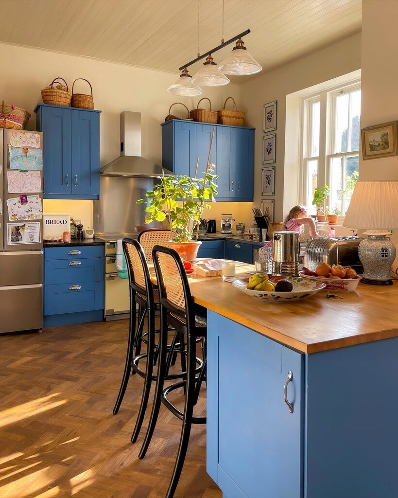 Modern kitchen with blue cabinets, wooden island, and stainless steel appliances.