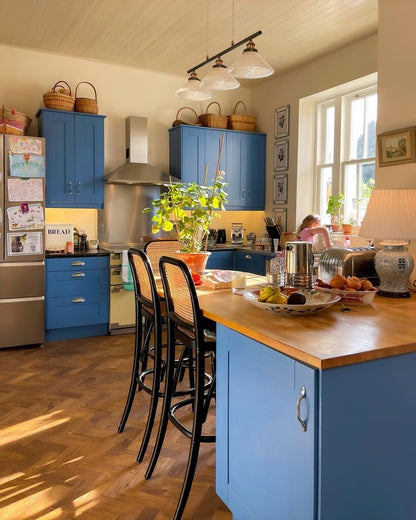 Modern kitchen with blue cabinets, wooden island, and stainless steel appliances.
