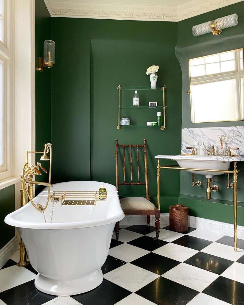 Bathroom with green walls, black and white checkered floor, freestanding bathtub, and sink.