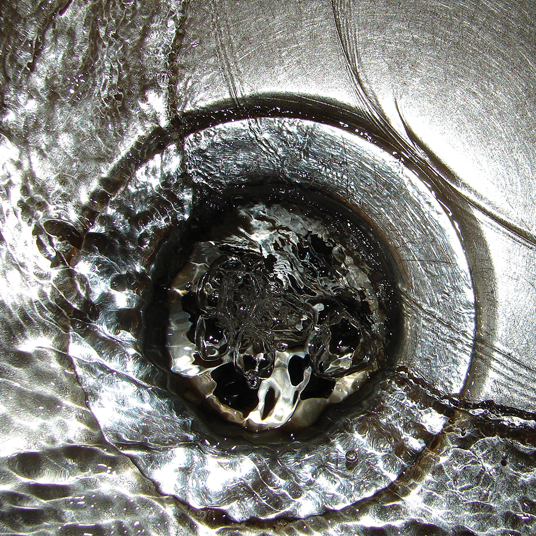 Close-up of a metal drain with swirling water