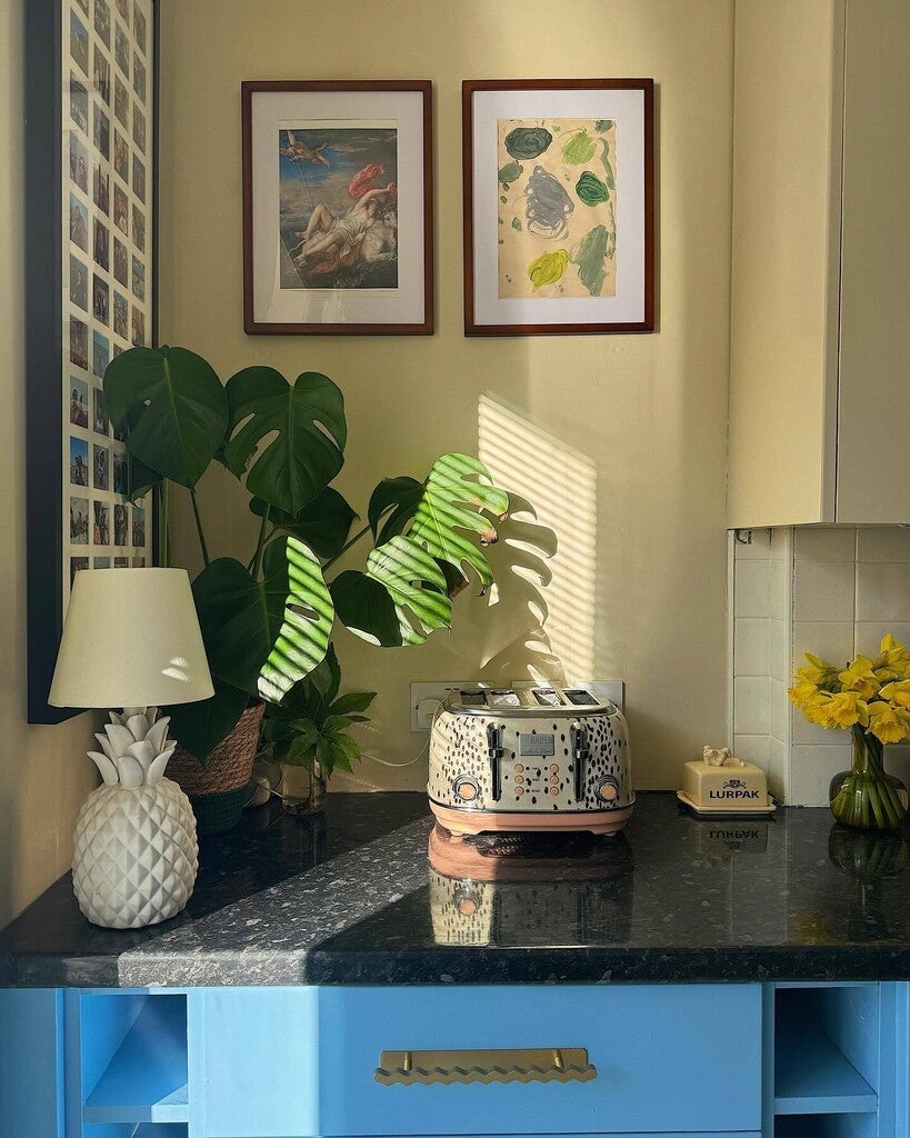 Kitchen counter with a toaster, lamp, and decorative items against a yellow wall.