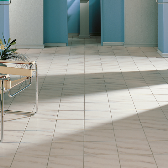 Tile floor with a chair and plant in a room with blue walls.