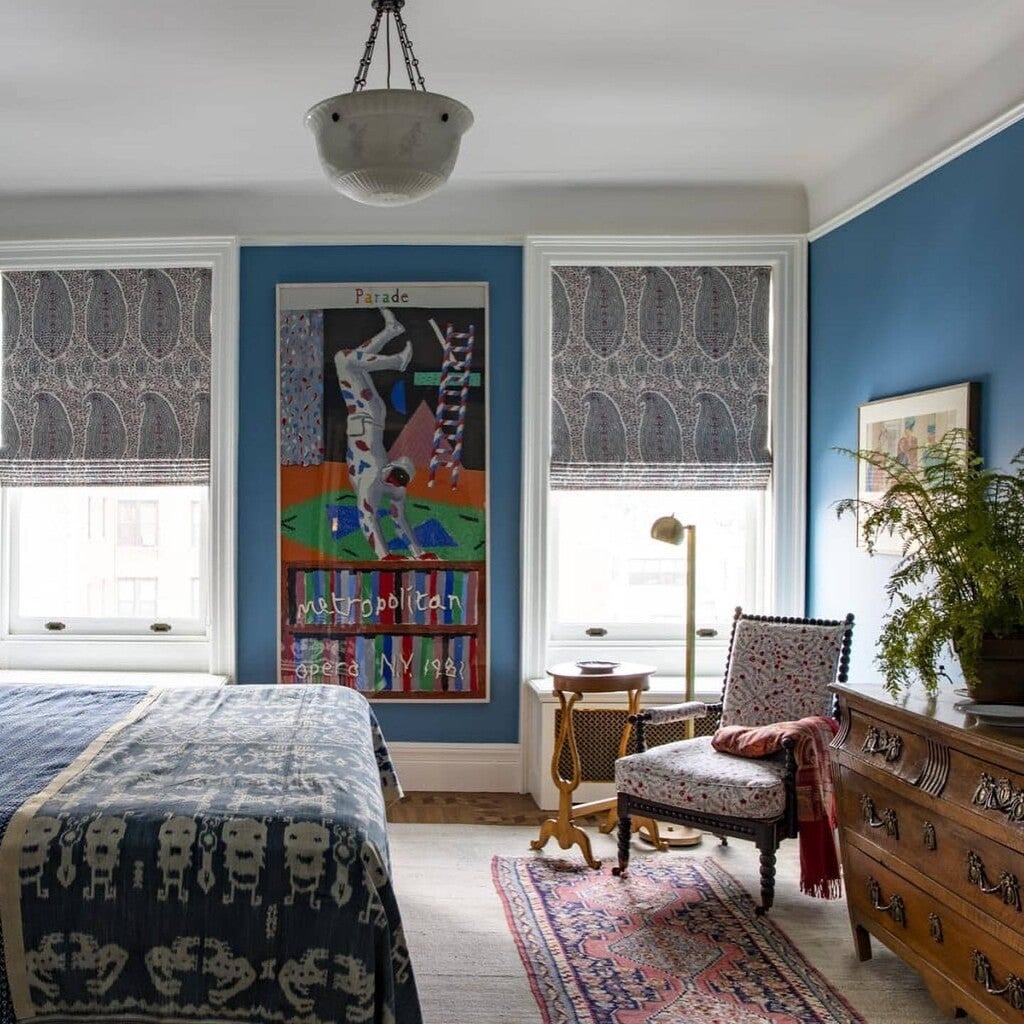 Room interior with blue walls, a bed, chair, and artwork.