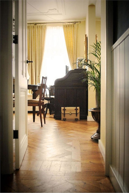 Narrow hallway leading to a room with a piano and large window