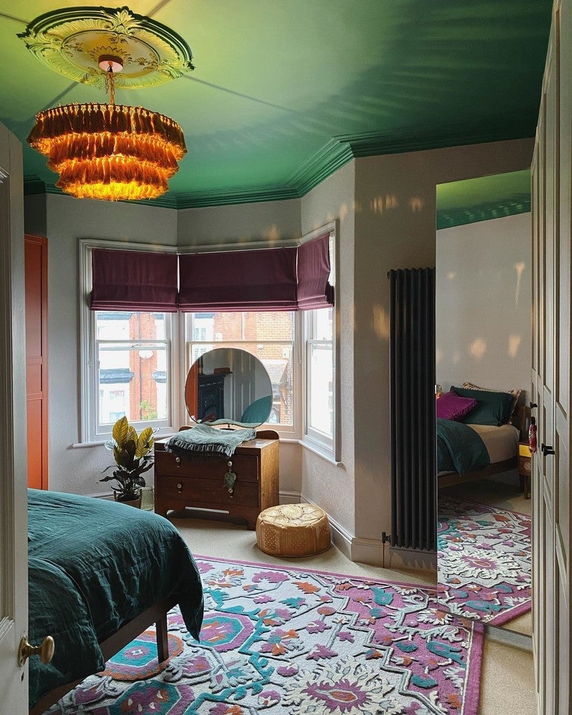 Colorful bedroom with green ceiling, patterned rug, and decorative lighting.