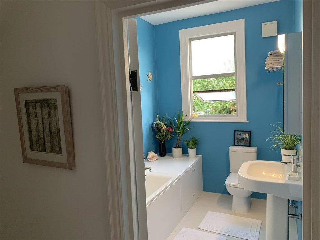 Bathroom with blue walls, white fixtures, and a window.