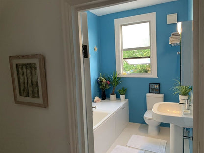 Bathroom with blue walls, white fixtures, and a window.