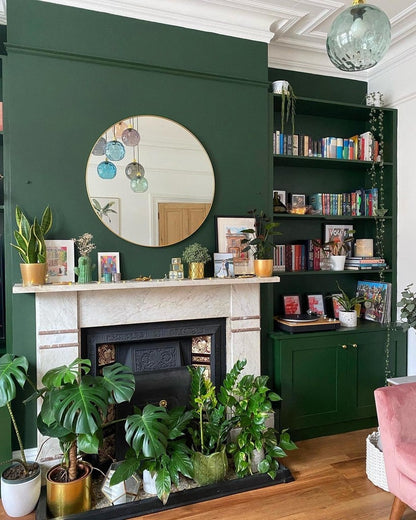 Living room with green walls, a fireplace, and bookshelf filled with books and decor.