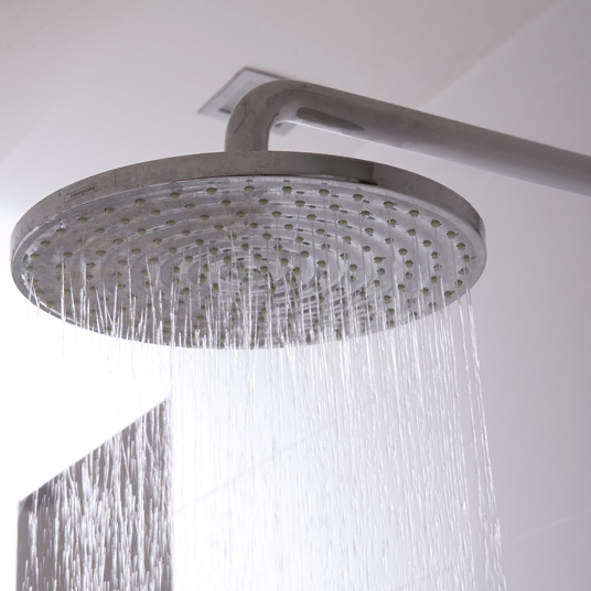 Metallic shower head with water flowing in a bathroom setting