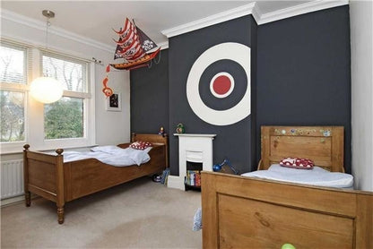 Children's bedroom with wooden beds, dark wall with target design, and toys.