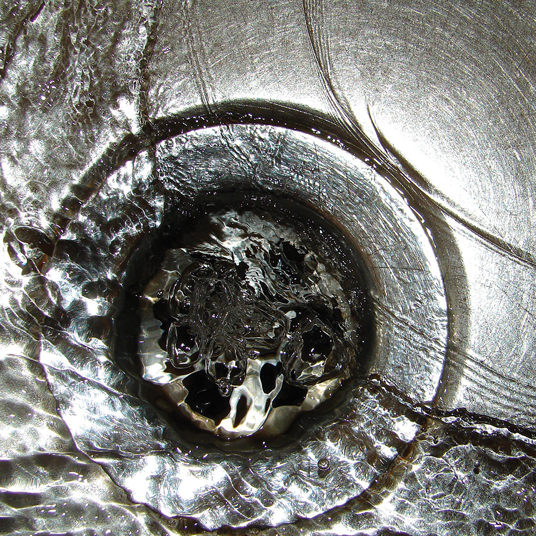 Close-up of a metallic drain with water flowing through it
