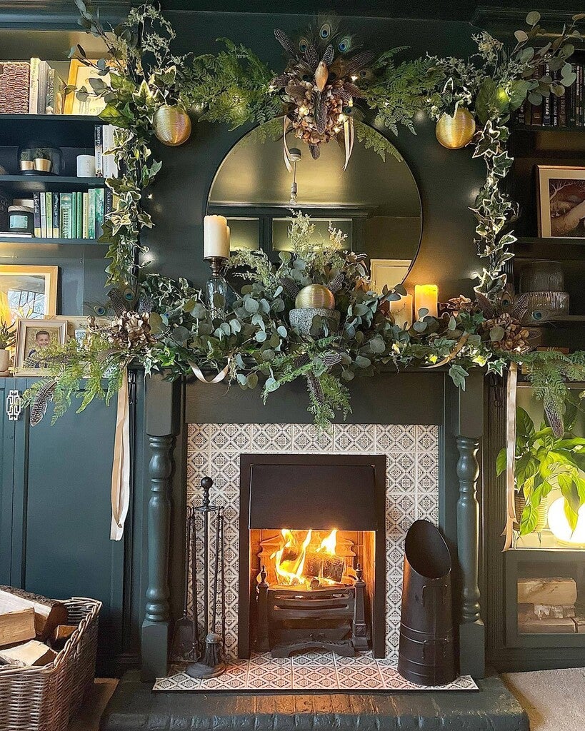 Decorative fireplace with greenery, candles, and a mirror above it.