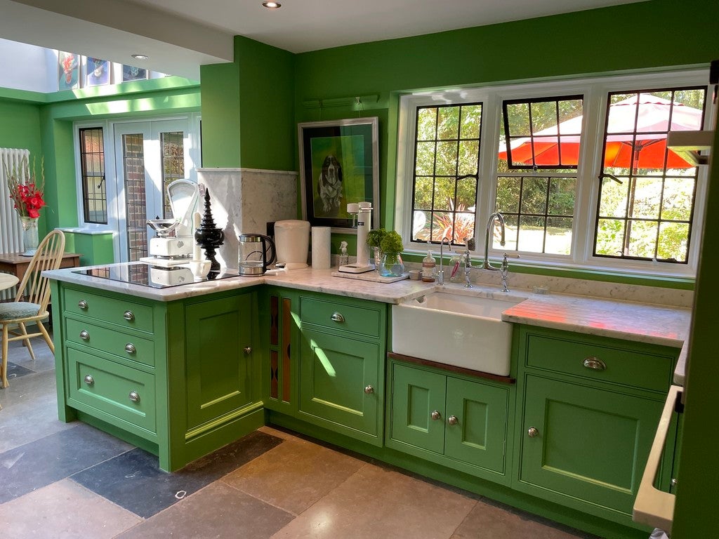 Green kitchen with white appliances and large windows