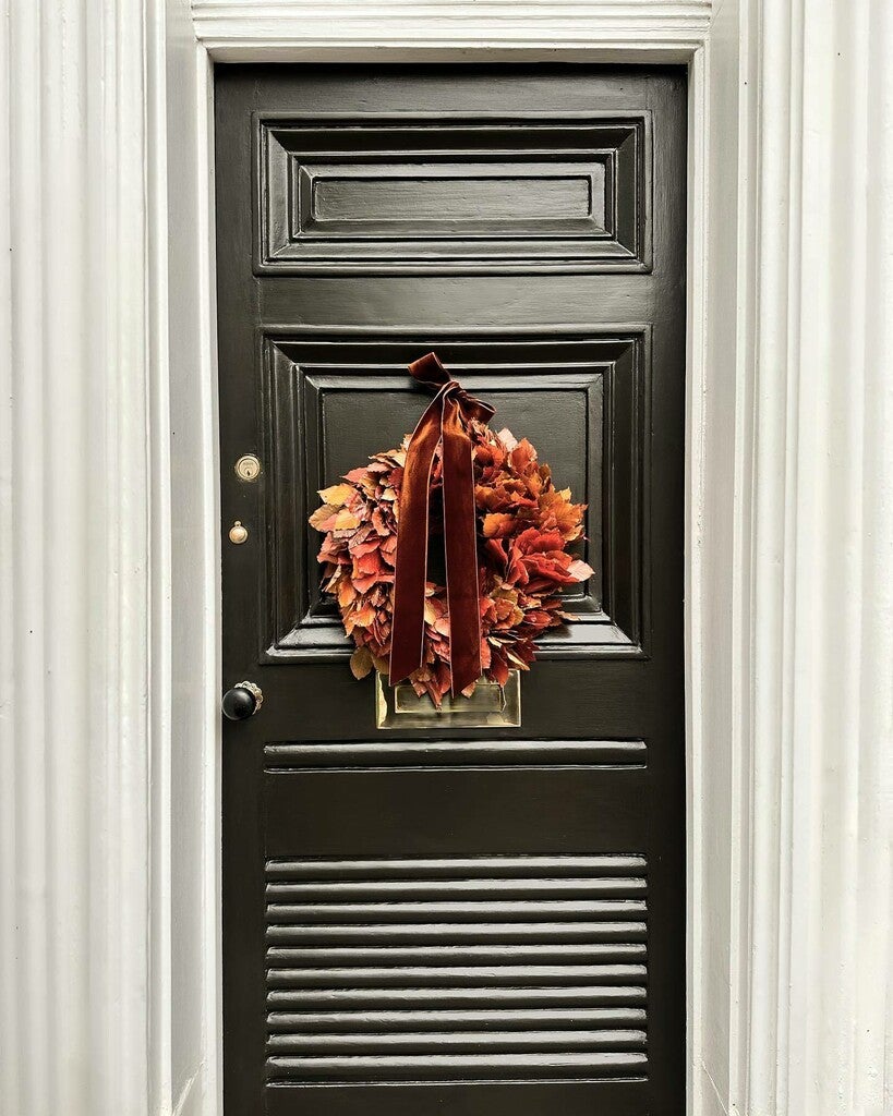 Black door with a decorative wreath and ribbon
