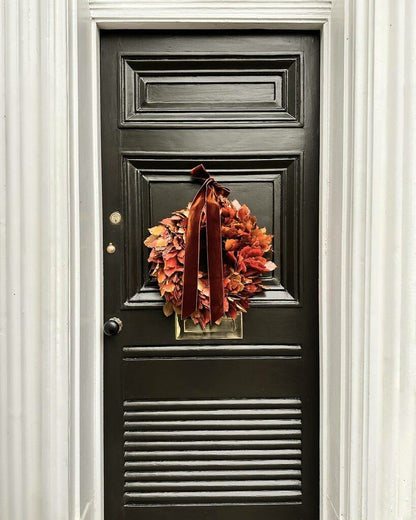 Black door with a decorative wreath and ribbon